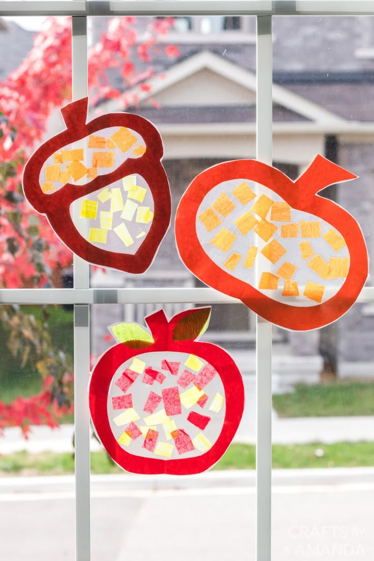 three cut out pieces of fruit sitting on top of a window sill in front of a house