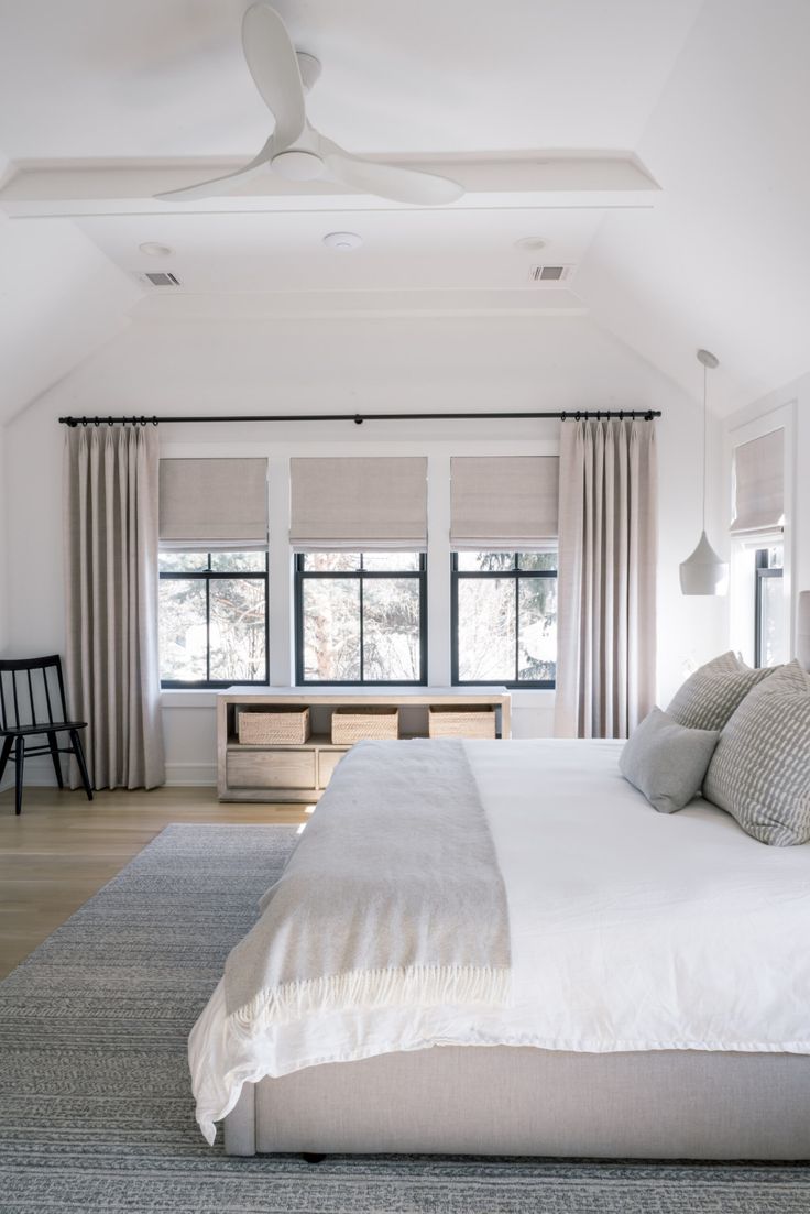 a large white bed sitting in a bedroom next to a window