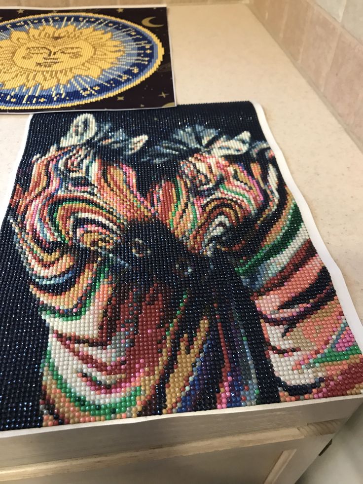 two pieces of beaded artwork on a counter top