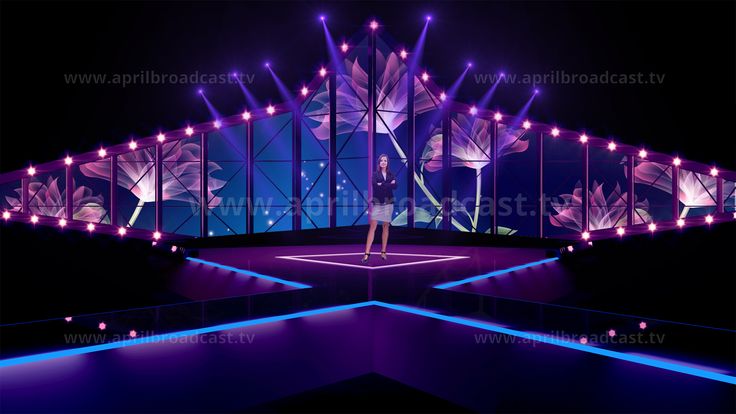 a woman is standing in front of a stage with lights and flowers on the walls