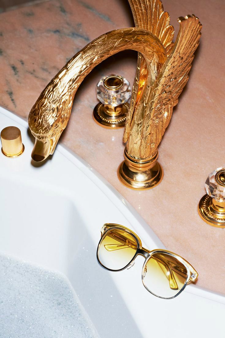 a pair of sunglasses sitting on top of a bath tub next to a golden bird