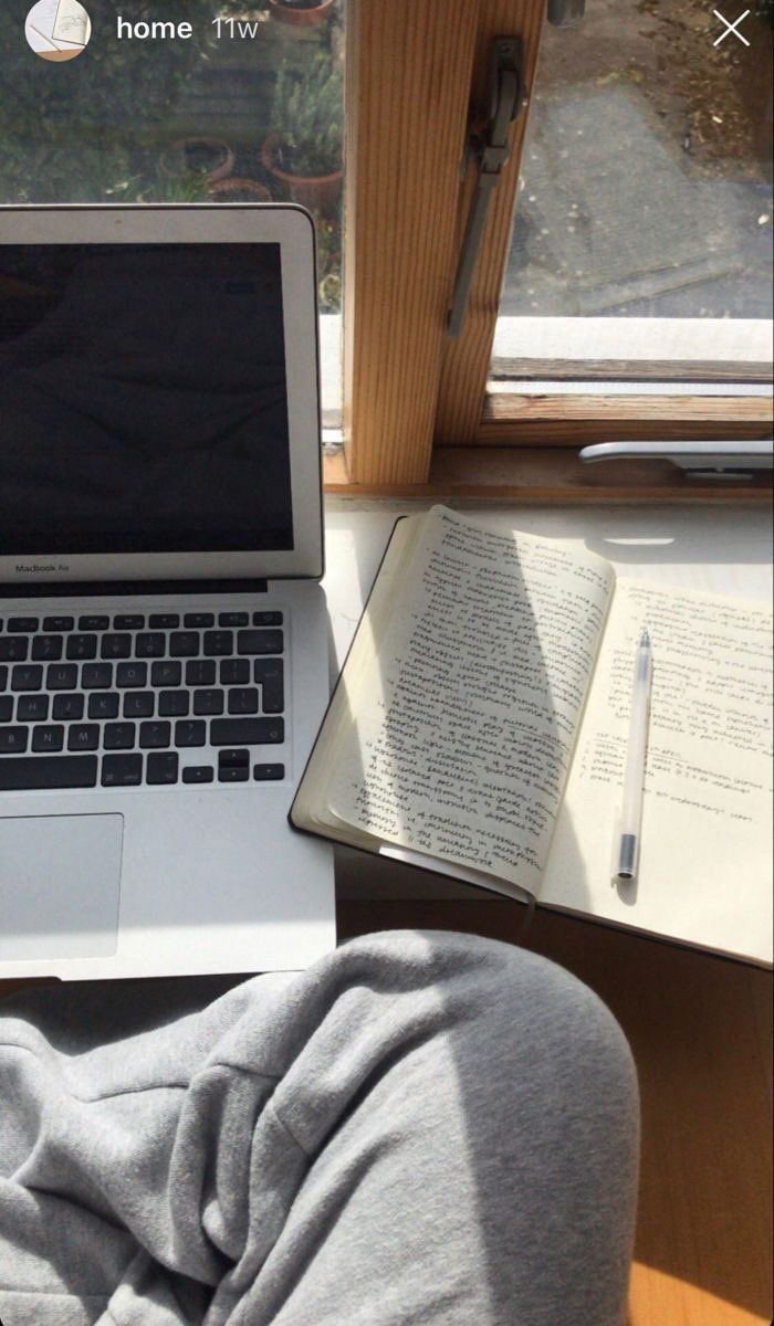 an open laptop computer sitting on top of a desk next to a book and pen