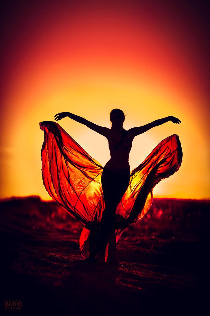 a woman is dancing in the sunset with her arms spread out and hands extended up