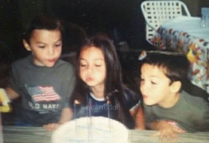 three children blowing out the candles on a cake