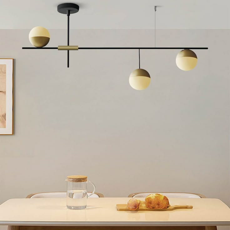 an image of a dining room setting with food on the table and hanging lights above it