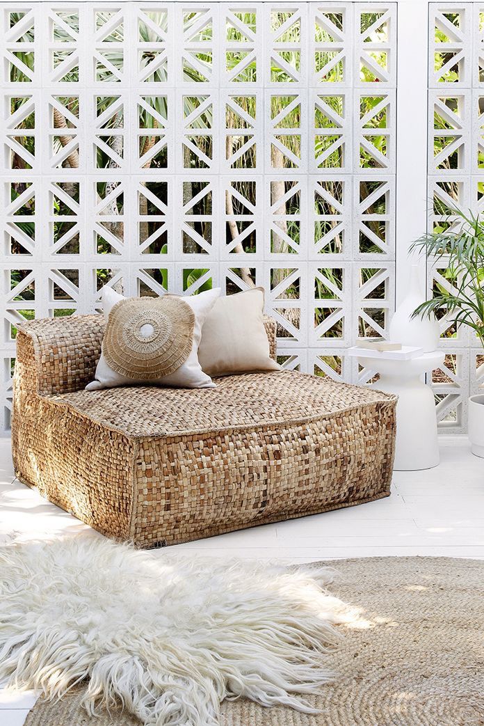 a living room with white walls and wicker furniture on the floor in front of a trellis