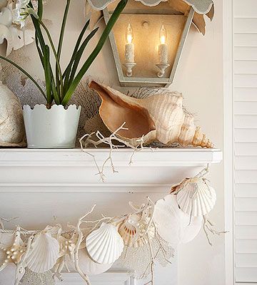 a fireplace mantel with seashells and flowers on it, along with candles