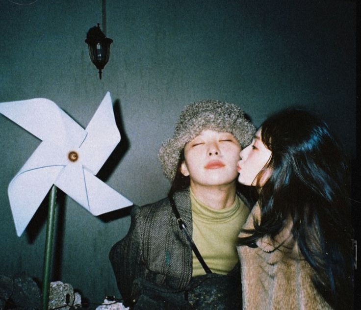 two people are kissing in front of a pinwheel and paper windmill on the wall