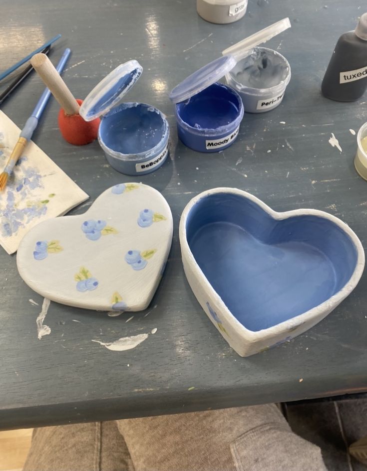 the heart shaped dish is sitting on the table next to other paint and craft supplies