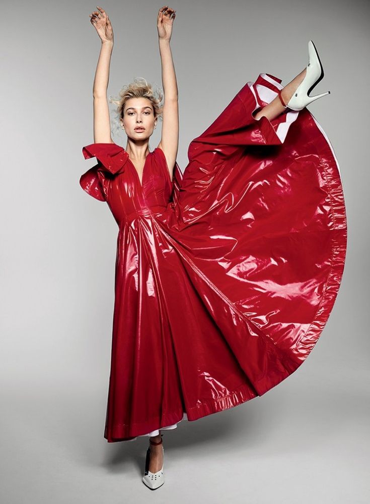 a woman in a red dress with her arms up and legs spread out, posing for the camera