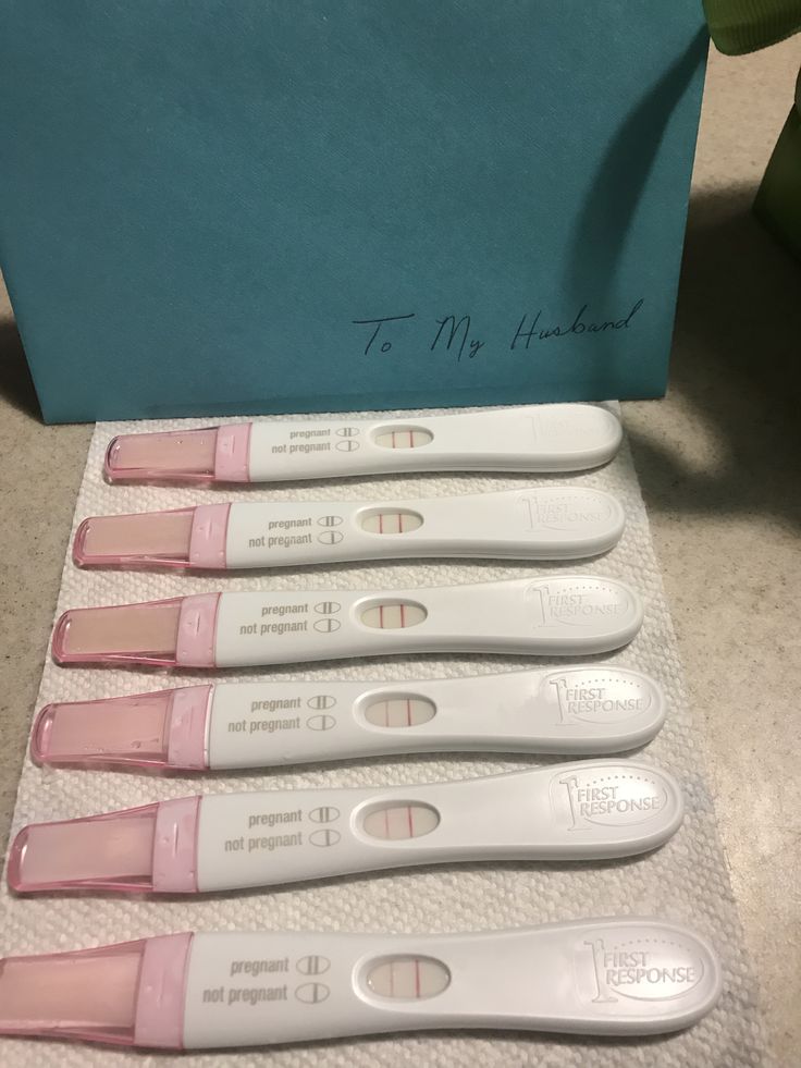 four pink and white toothbrushes sitting on top of a table next to a blue box