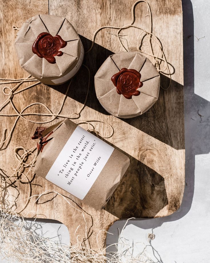 two brown wrapped cakes sitting on top of a wooden cutting board next to each other