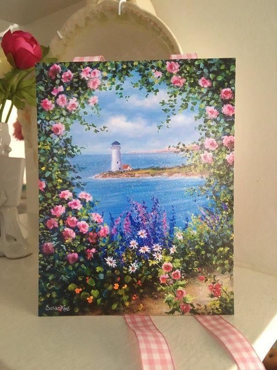 there is a card with flowers and a lighthouse in the background on a white shelf