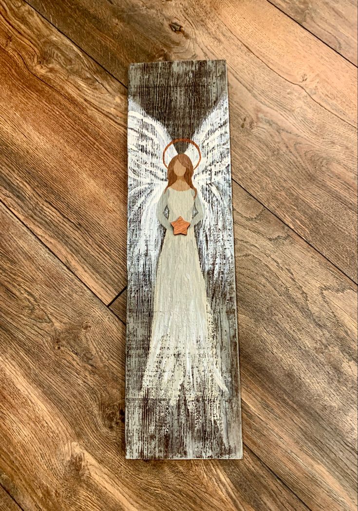 an angel painted on top of a wooden plaque