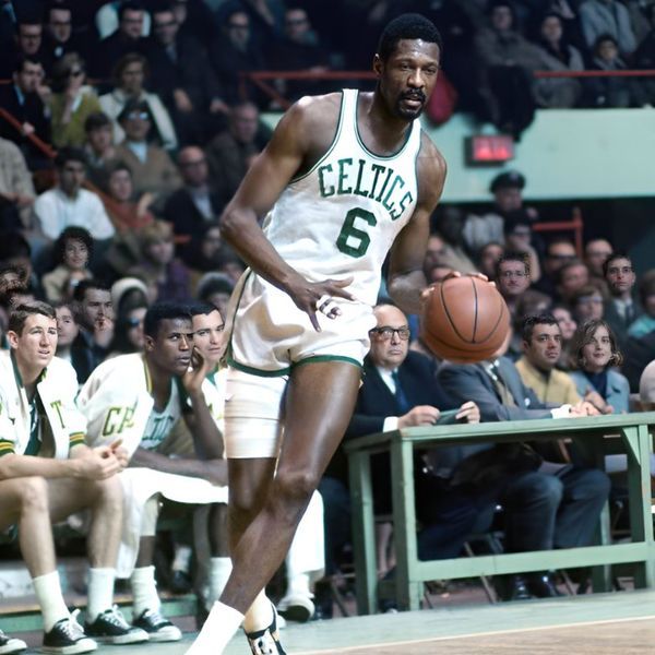 a basketball player dribbles the ball while standing in front of an audience at a sporting event