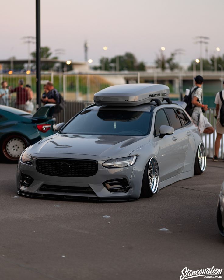 a car with a surfboard on the roof parked in a parking lot next to other cars