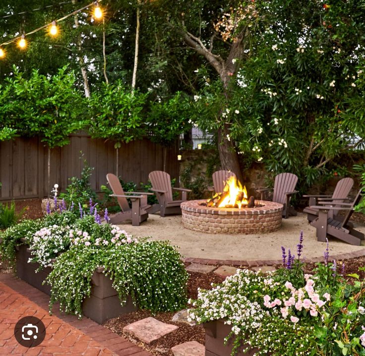 an outdoor fire pit surrounded by chairs and flowers