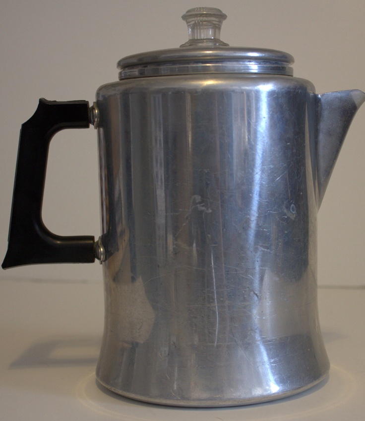 a silver coffee pot sitting on top of a white counter next to a black handle