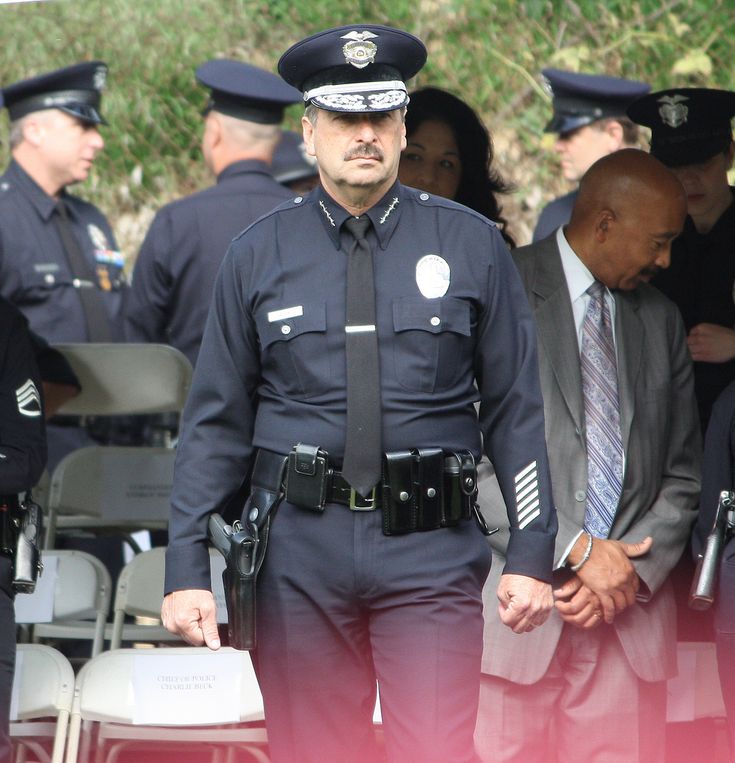 two police officers standing next to each other in front of people wearing suits and ties