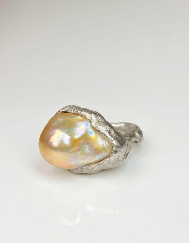 This extraordinary ring features a large freshwater baroque pearl with captivating champagne iridescence, making it truly one-of-a-kind. The avant-garde design of the ring, combined with its artisan-style textured band, adds a funky touch. The pearl's iridescence shines prominently, enhancing its unusual elegance！ This is Ready-to-ship item! -Gems informations Large freshwater baroque pearl: No.3 -Size US 7 1/2, can be resized width of band: about 6mm setting: 22-29mm -Materials 925 Sterling -Packaging Your ring will arrive in a beautiful surprise gift box Customization Each pearl has been handpicked by me and boasts distinctive features! Please refer to the photos of pearls in the image to choose your preferred color and contact me to inquire. If you would like to explore more options for Fresh Water Baroque Pearl, Fresh Water Pearl Ring, Baroque Pearl Ring, Unusual Wedding Rings, Chunky Pearls, Freshwater Pearl Ring, Pearl Color, Baroque Pearls, Pearl Ring