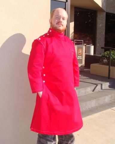 a man in a red coat standing next to a wall with his hands on his hips