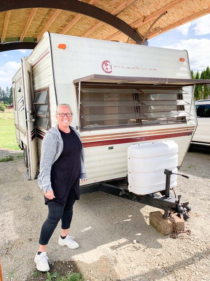 a woman standing next to an old camper