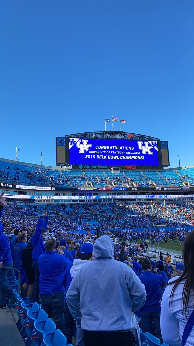 a stadium filled with lots of people sitting in blue chairs and watching a football game