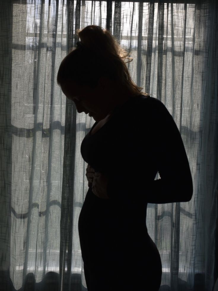 a pregnant woman standing in front of a window