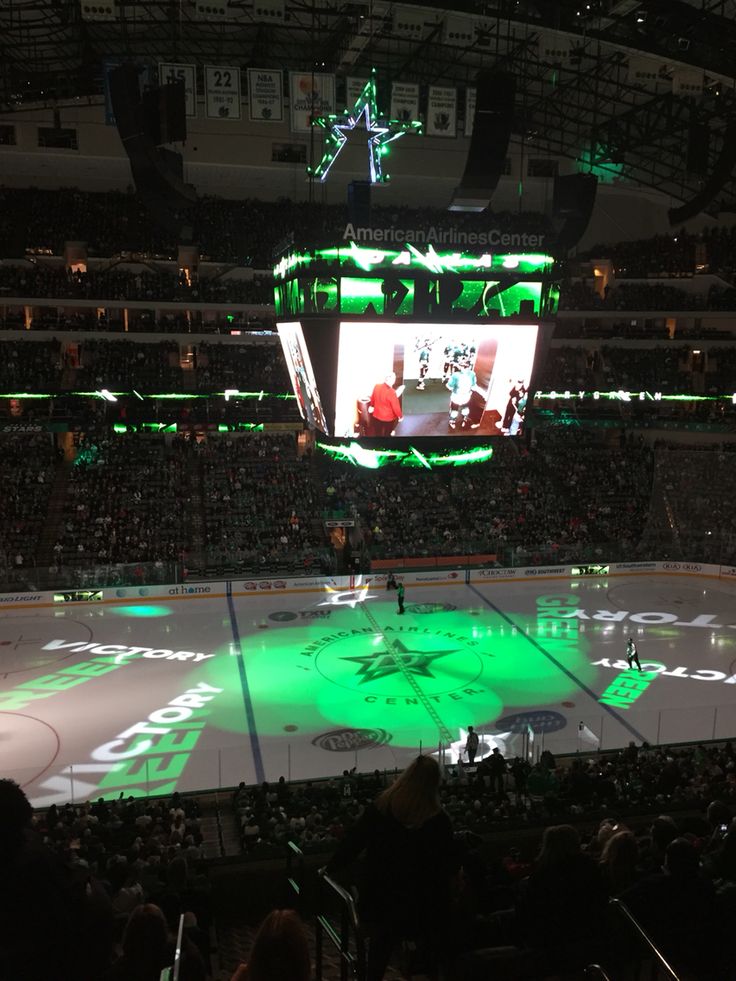 an ice hockey game is being played on the big screen in the center of the arena