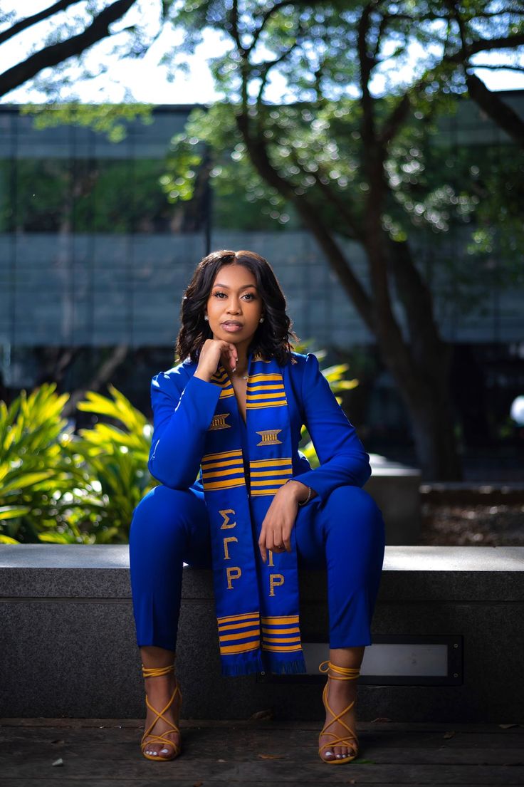 a woman is sitting on a bench wearing blue and yellow clothing with her hand under her chin