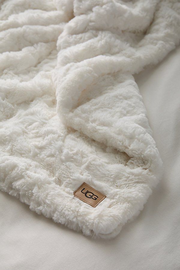 a white blanket that is laying on top of a bed with a tag in it