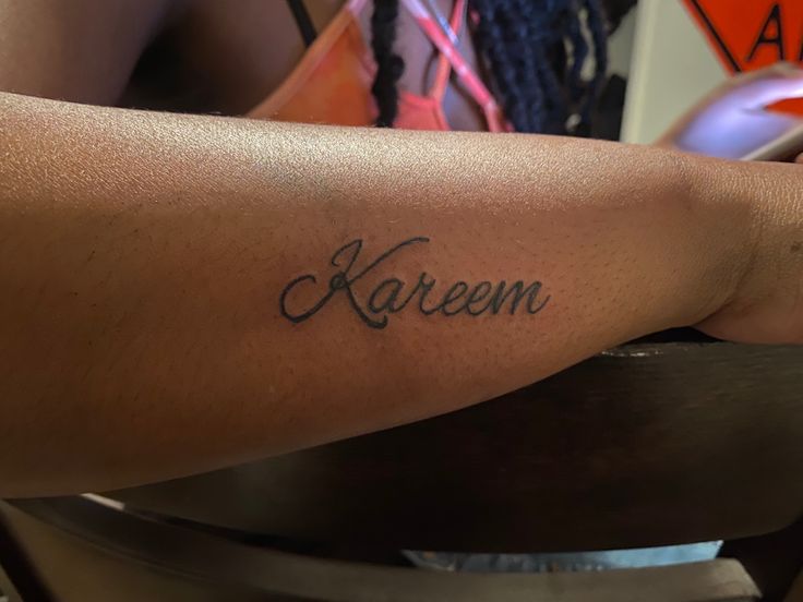 a woman's arm with the word karem tattooed on it