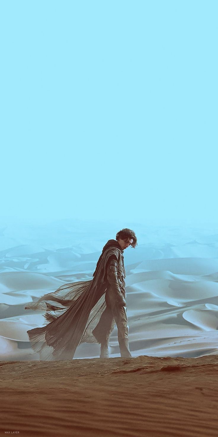 a man walking across a desert covered in sand