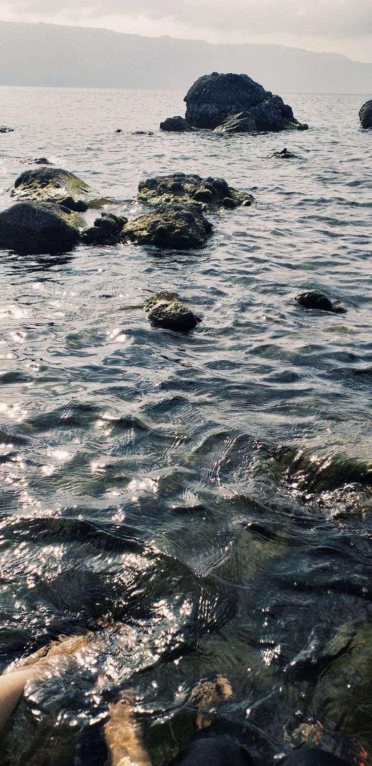 some rocks in the water and one is laying on it