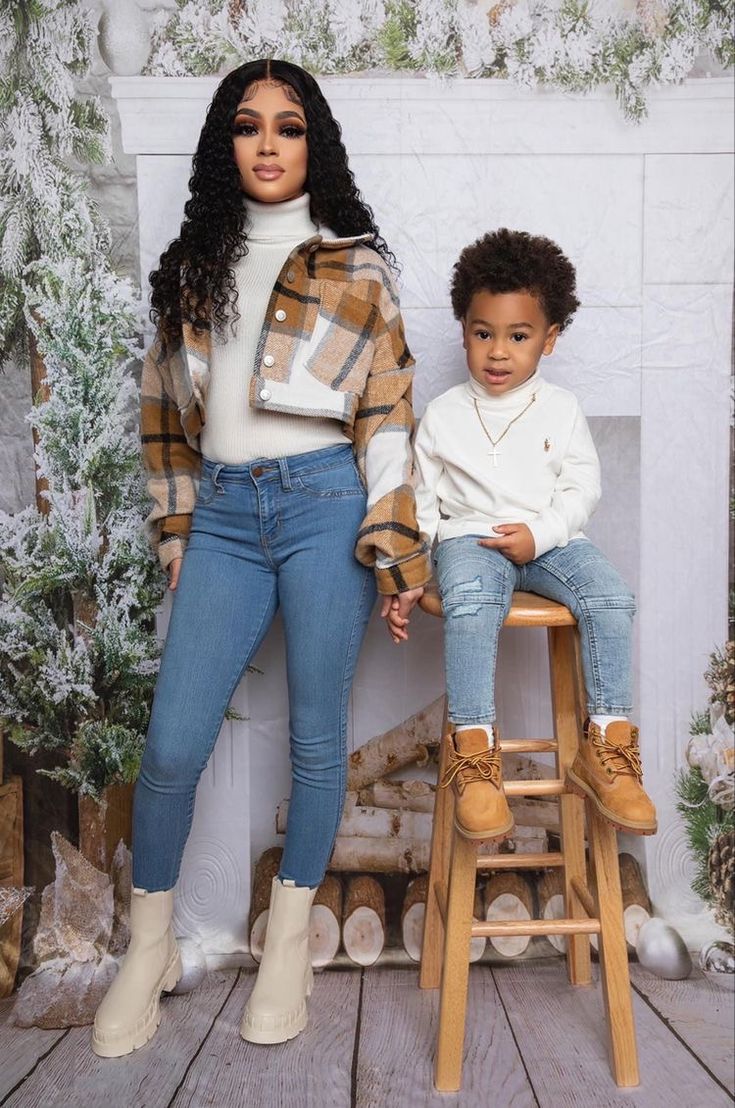 two children sitting on stools in front of a fireplace with christmas decorations behind them