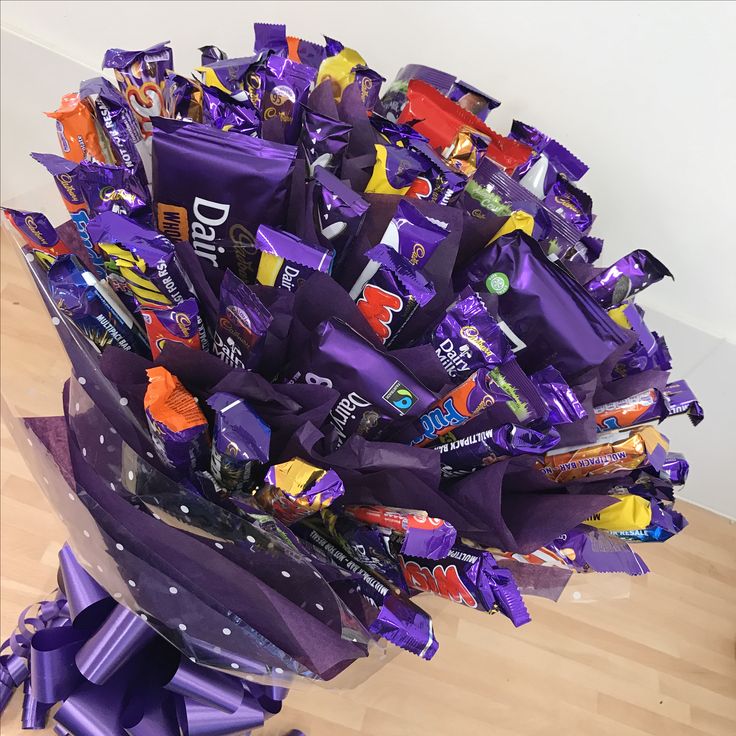 a bouquet of purple candy wrappers on top of a wooden floor next to a wall