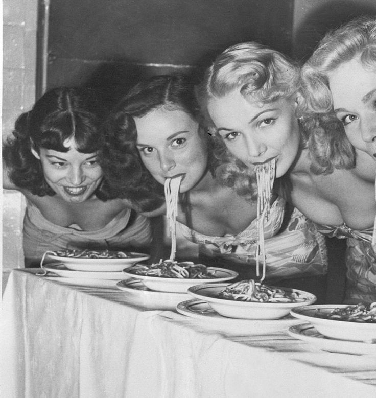 four women are eating spaghetti at a table