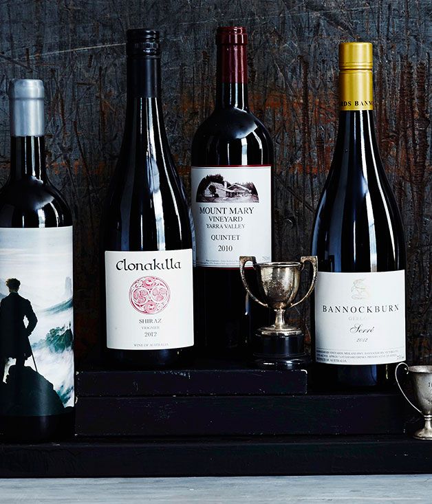 several bottles of wine sitting next to each other on a shelf with a trophy cup in front of them