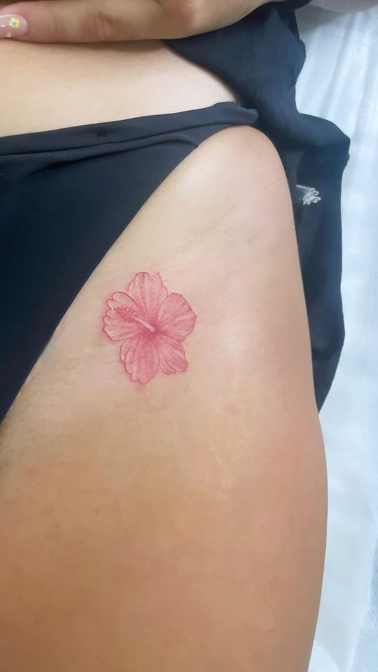 a woman's stomach with a pink flower tattoo on her lower back and side