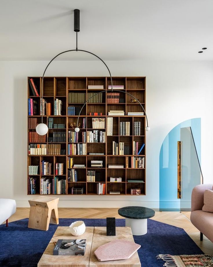 a living room filled with furniture and bookshelves next to a blue carpeted floor