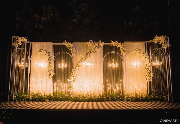 an outdoor wedding stage with chandeliers and flowers