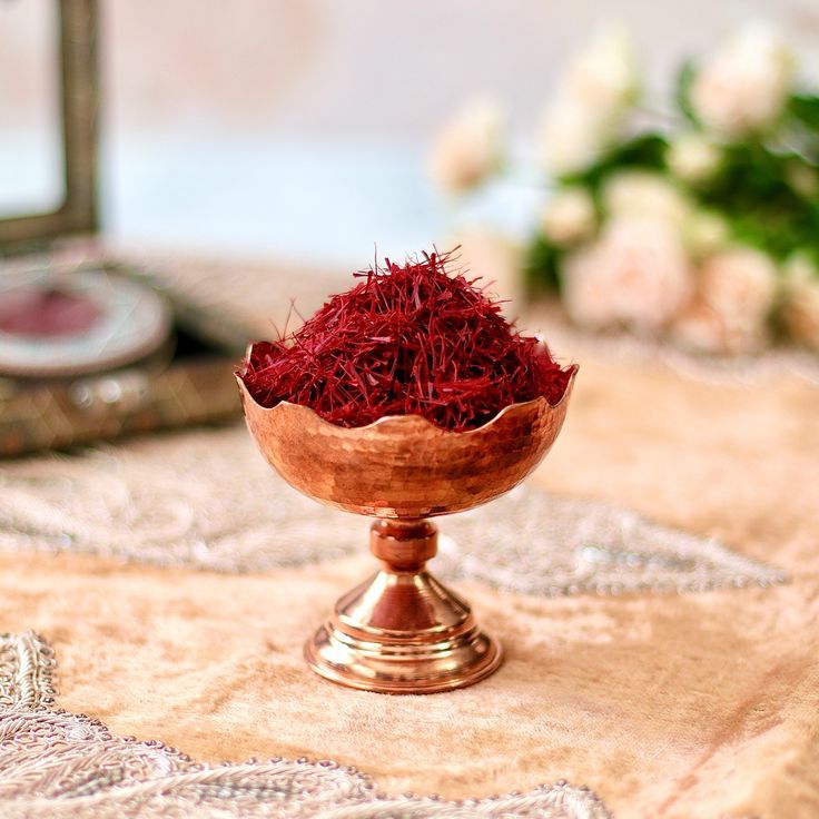 a wooden bowl filled with red flowers on top of a table