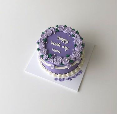 a birthday cake with purple frosting and roses on it sitting on top of a card