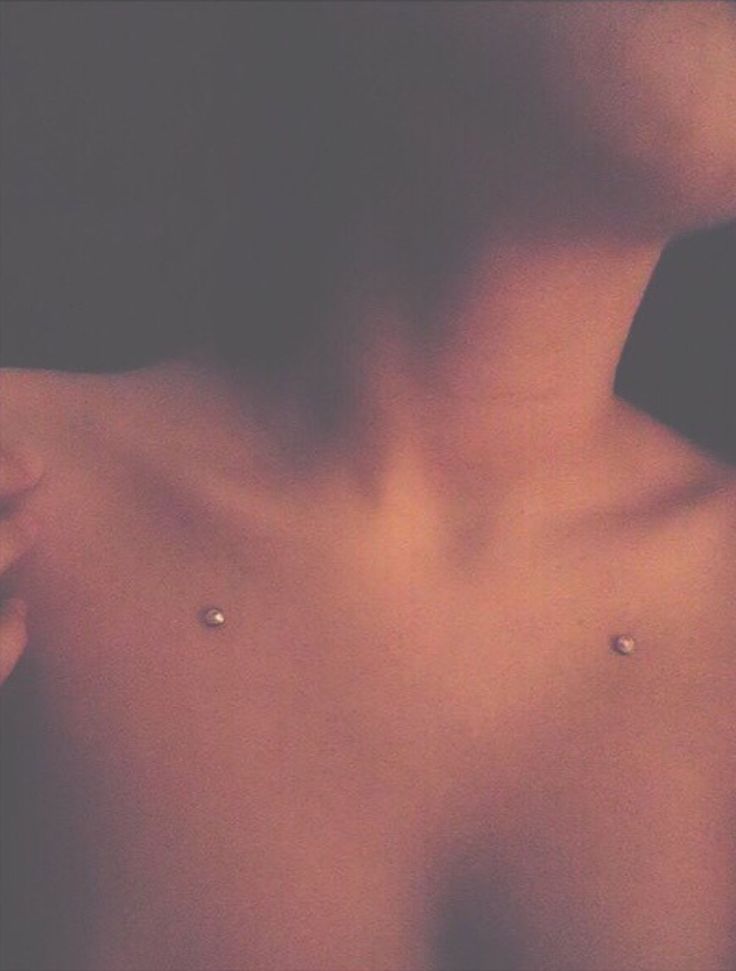 a close up of a person's chest with three piercings on it,