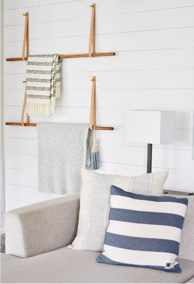 a couch with pillows and blankets hanging on the wall next to two wooden pegs