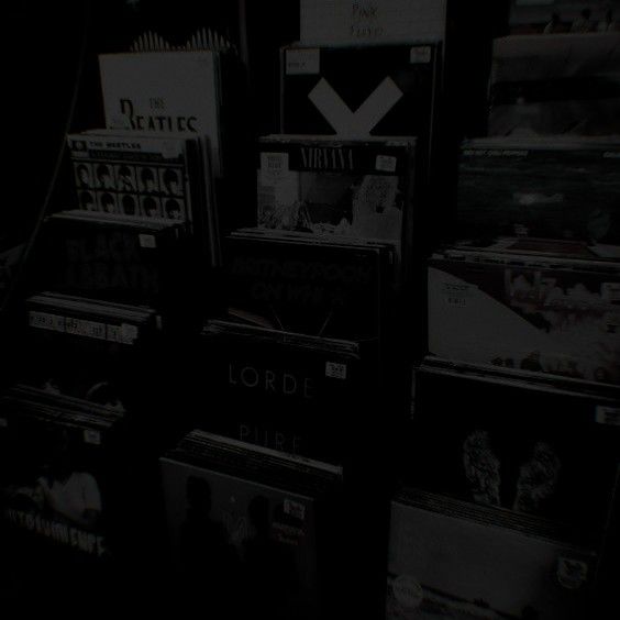 several records are stacked up on the floor in front of a dark room with lights