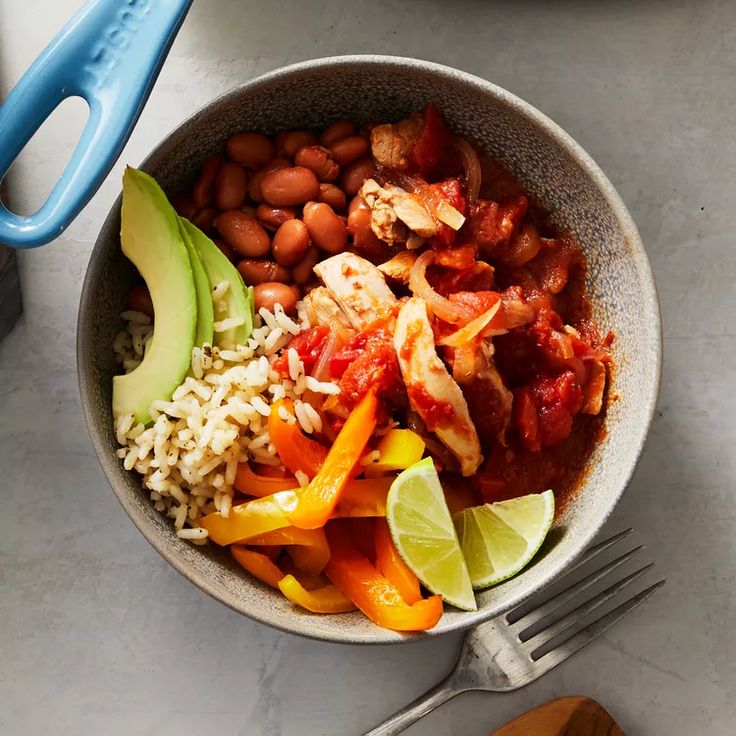 a bowl filled with beans, rice and avocado on top of a table