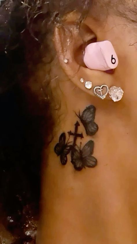 a close up of a person's ear with butterflies on it and a cross behind the ear