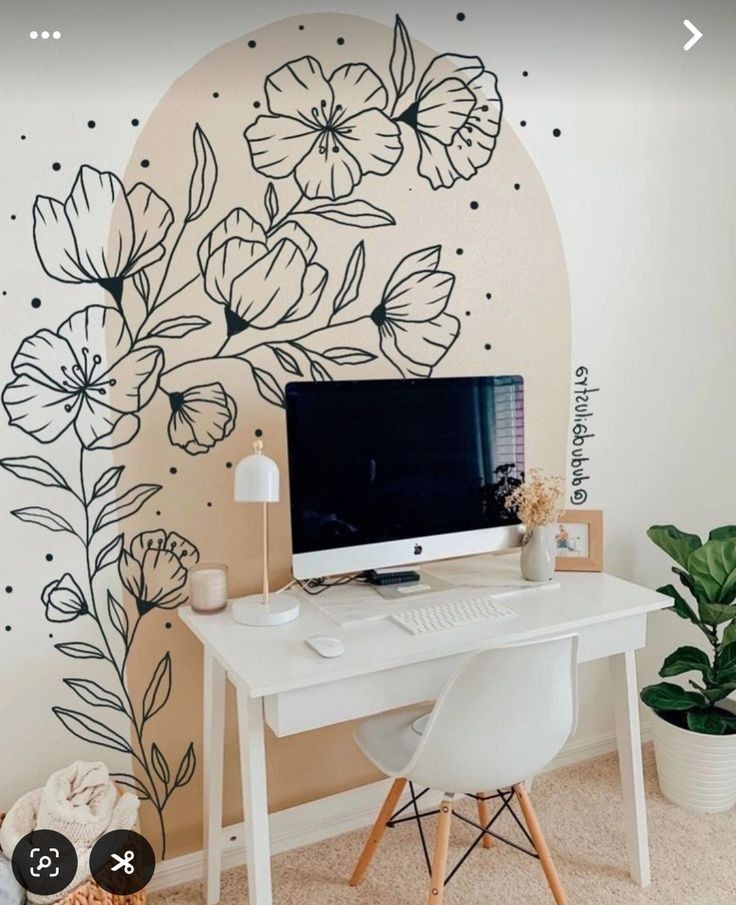 a desk with a computer on top of it in front of a flower wall mural