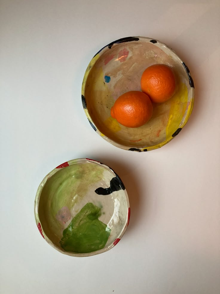 two bowls with oranges in them on a table